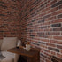 Modern living room corner featuring Babylon 3D faux brick wall panels behind a white armchair and wooden side table.